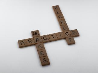 "Practice makes perfect" spelled out with Scrabble tiles